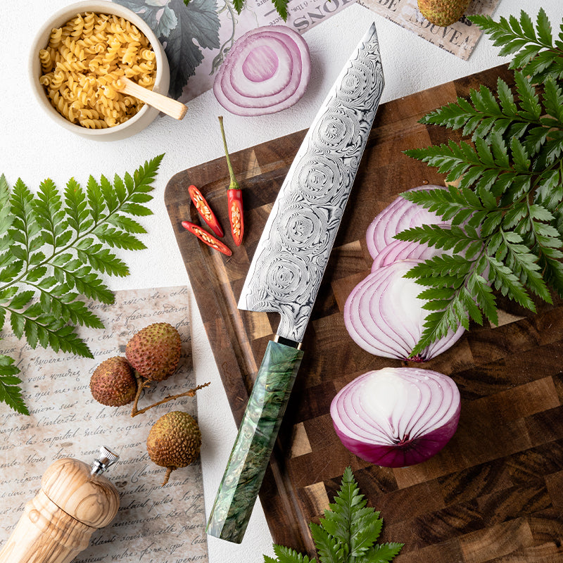 Decorative kiritsuke knife on a wooden cutting board with sliced red onions and herbs.