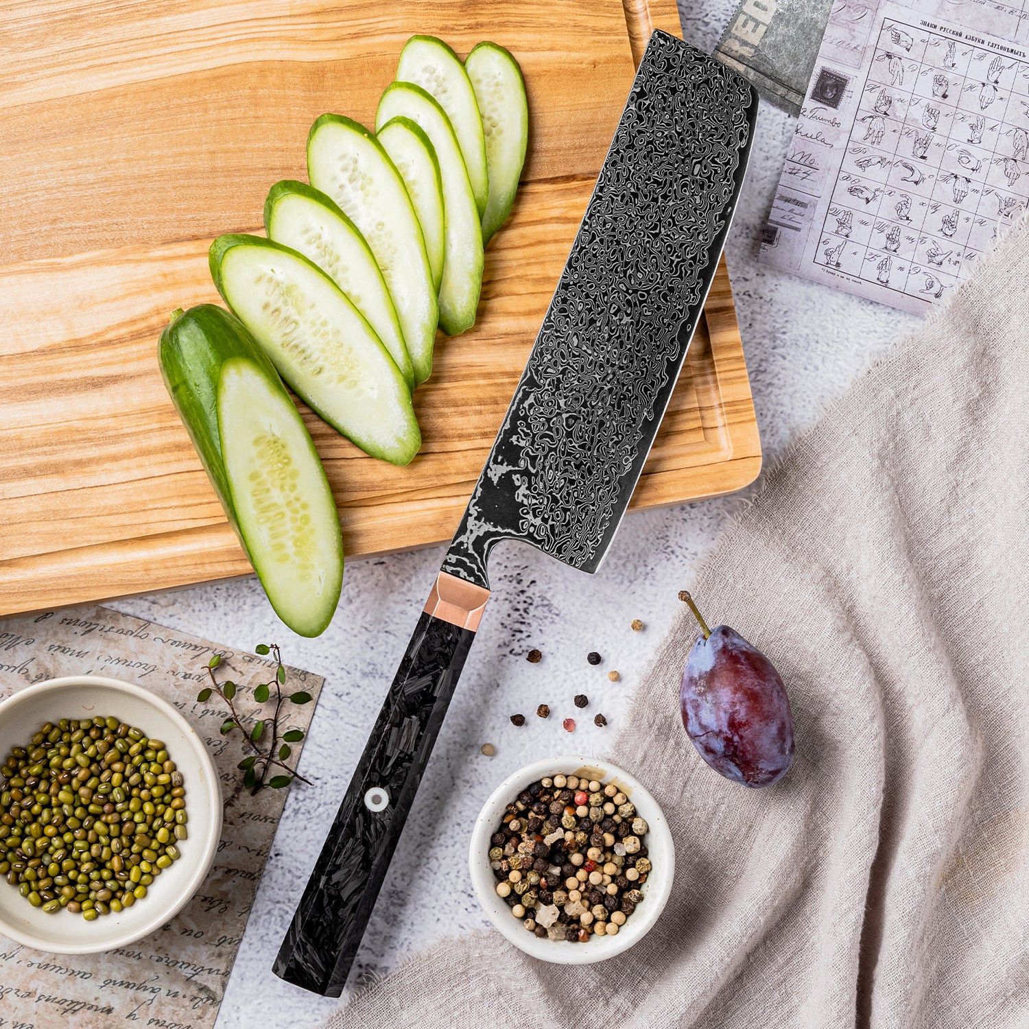 Knife on a wooden cutting board with sliced cucumbers, a plum, and small bowls of ingredients.