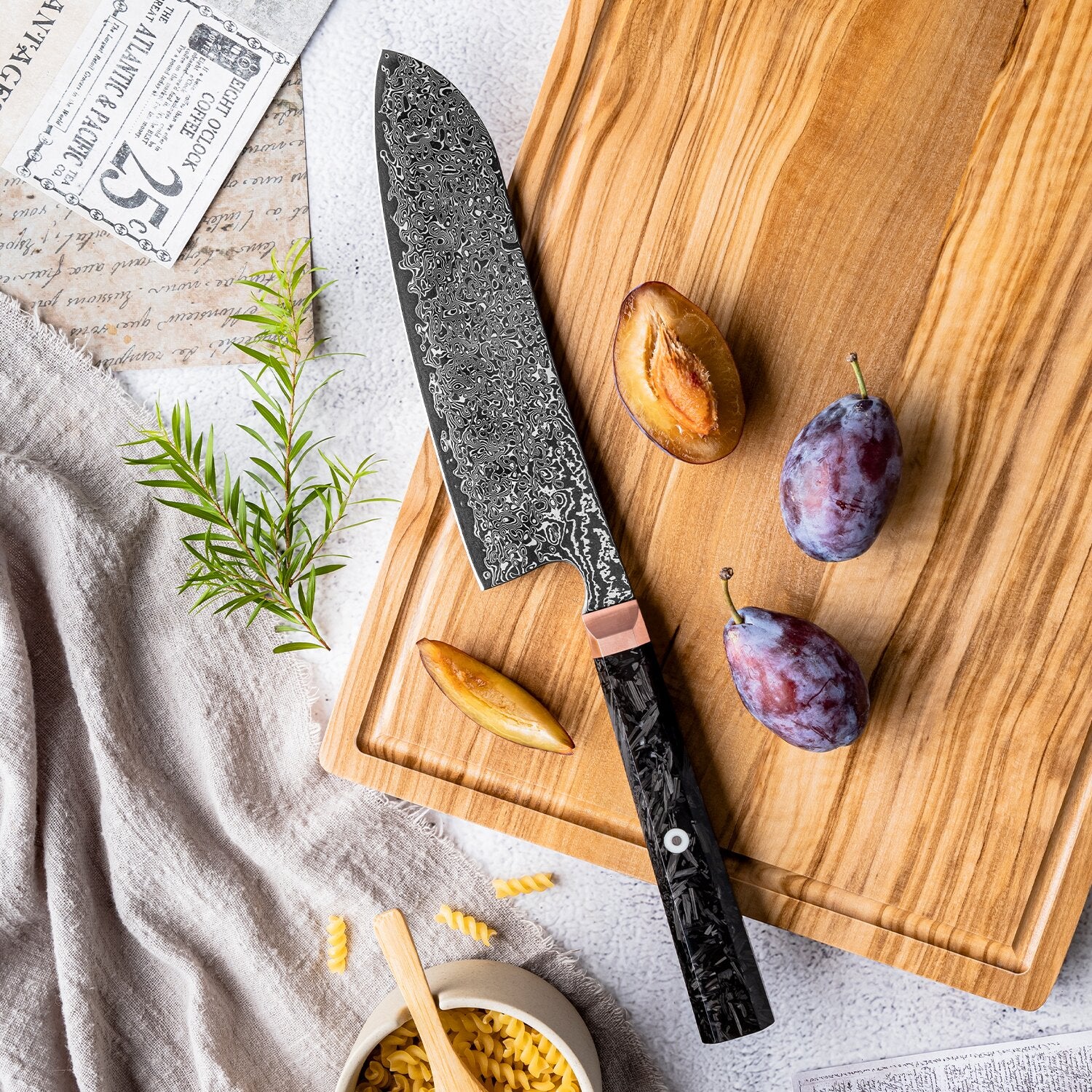 Decorative multi purpose knife on a wooden cutting board with plums and herbs
