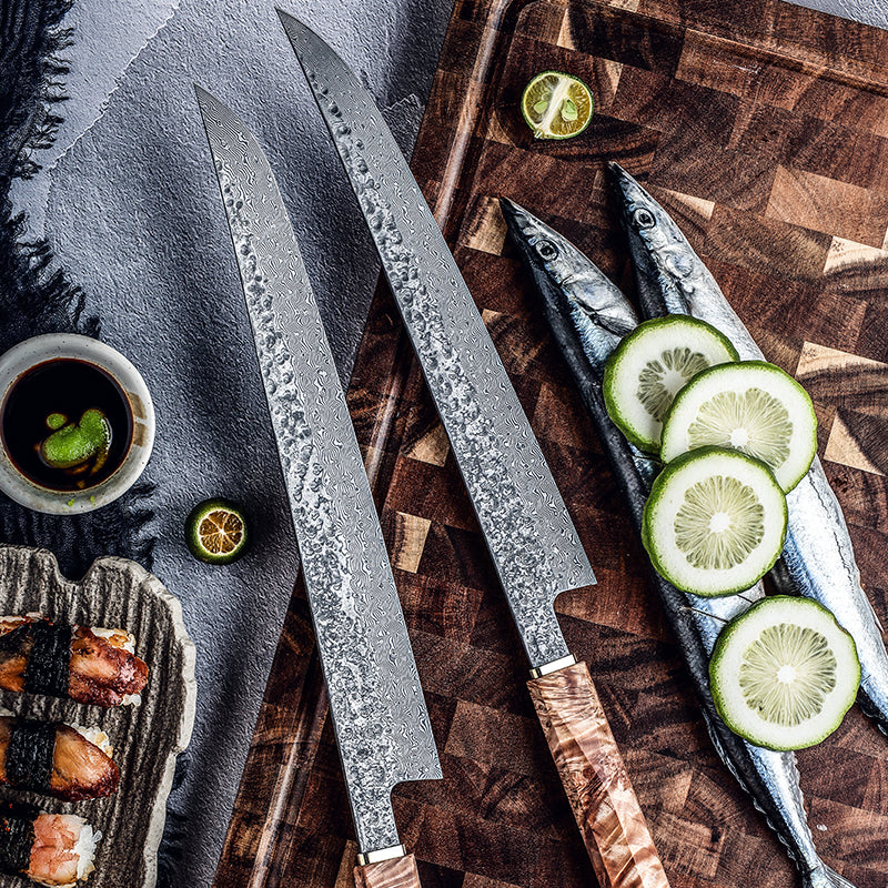 Three knives on a wooden cutting board with fish and lime slices.