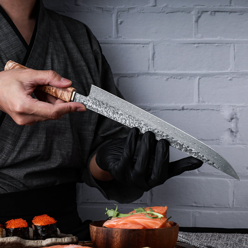 Person holding a large knife with a wooden handle over a table with sushi and salmon.