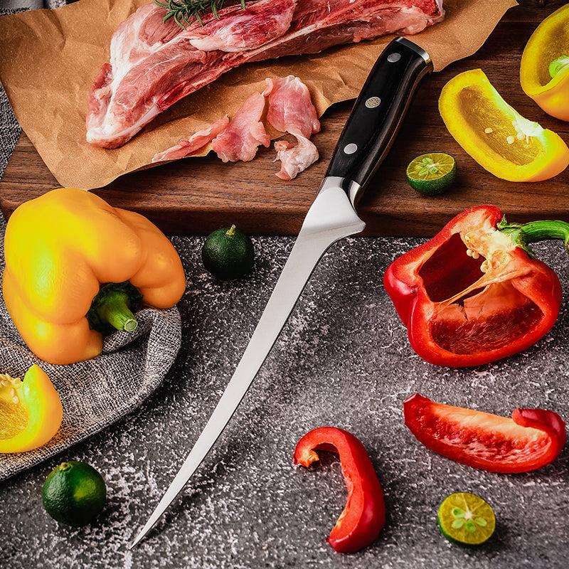 Raw meat on a wooden cutting board with a boning meat knife, surrounded by sliced red and yellow peppers and limes on a dark surface.