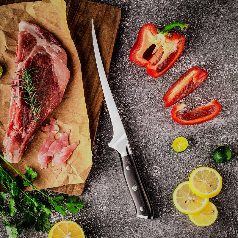 Raw meat with a german steel meat knife HIkari KNife, lemons, and peppers on a dark surface
