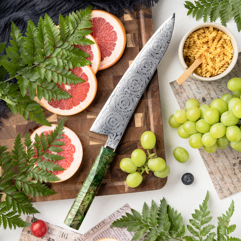 Decorative Rose Damascus Pattern knife with green handle on a wooden cutting board with fruits and foliage