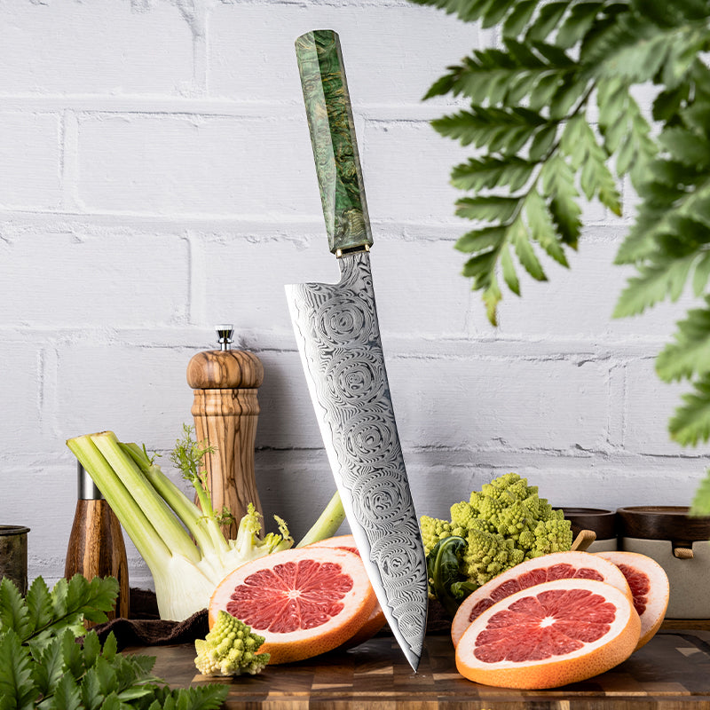 Decorative chef's knife with ROSE DAMASCUS PATTERN blade and green handle on a wooden cutting board with fruits and vegetables.