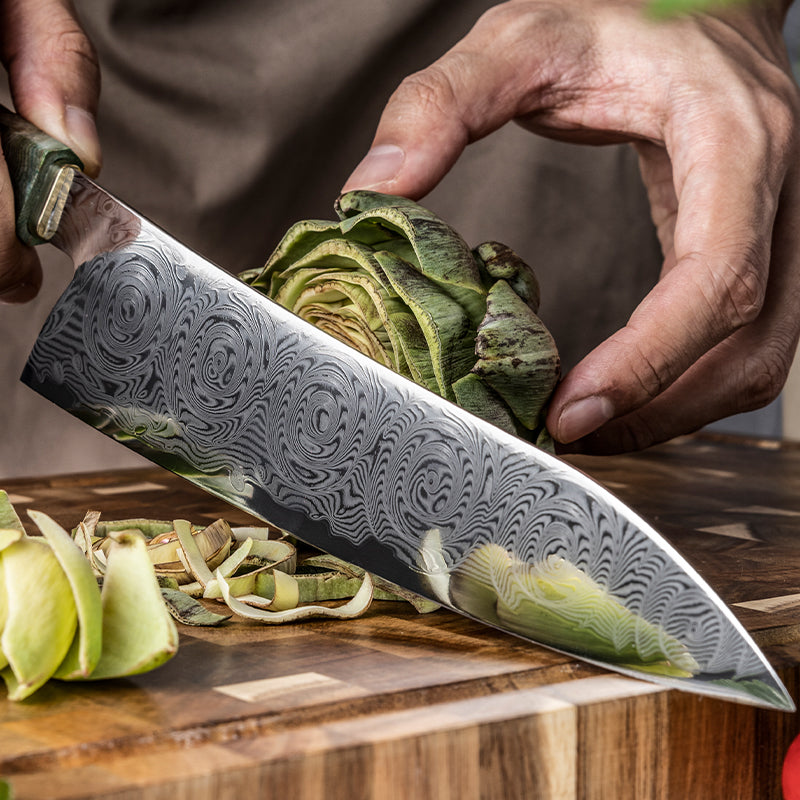 Person cutting artichoke with a decorative damascus knife on a wooden surface
