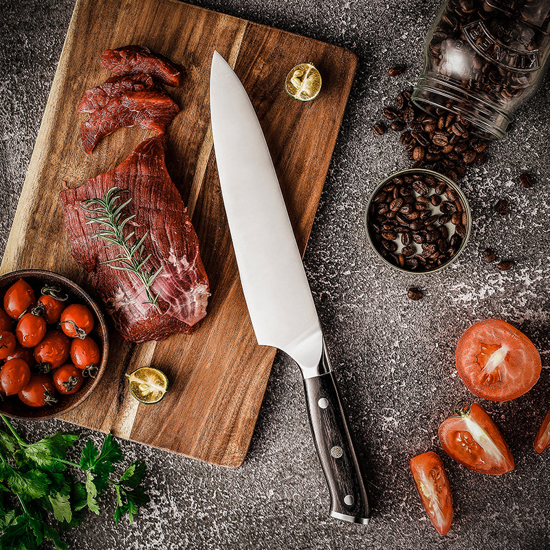 Hikari Knife german steel kitchen knife with Raw meat on a wooden cutting board with a knife, tomatoes, and spices on a dark surface.
