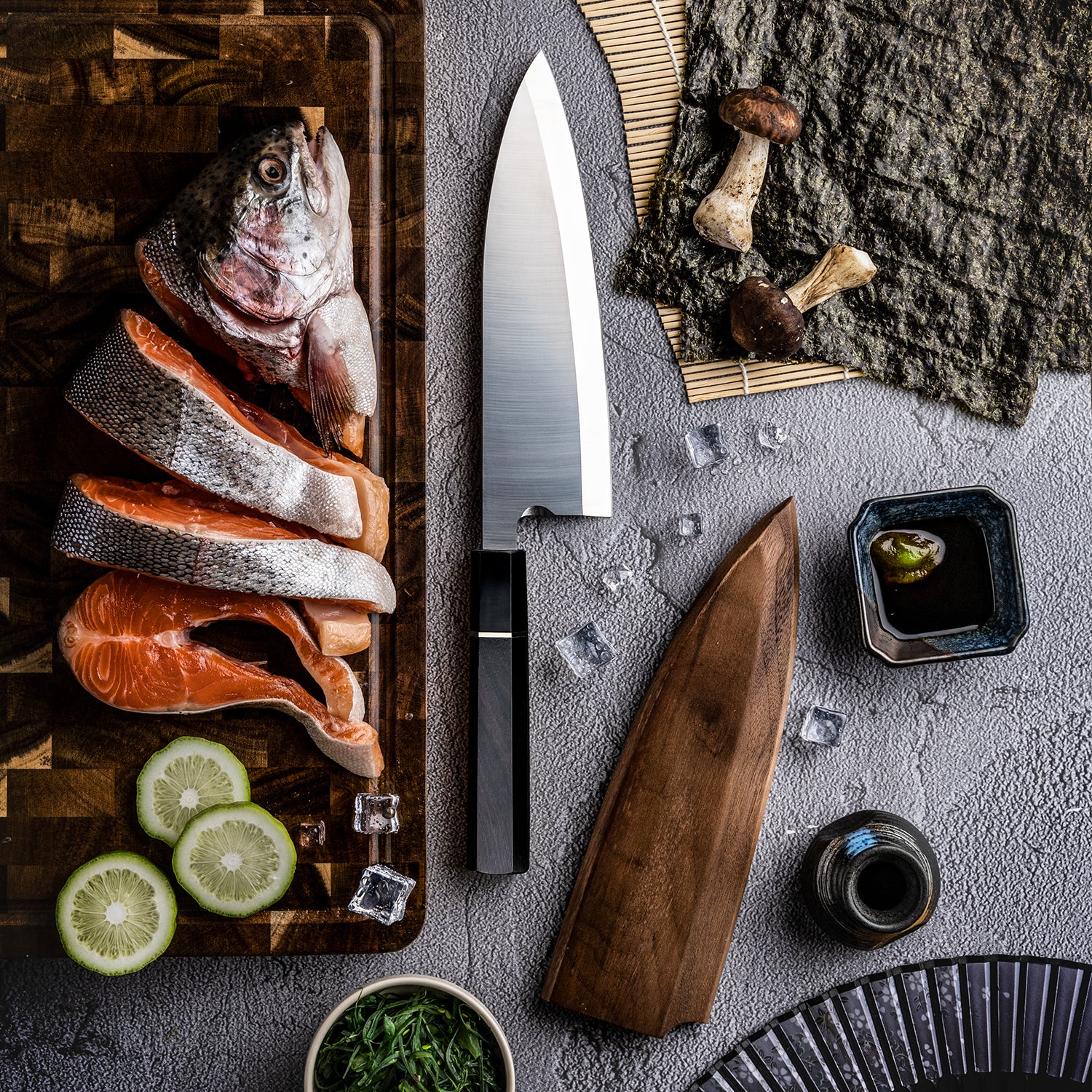 Hikari Japanese Deba knife with Raw fish on a cutting board, ingredients, and a gray surface.