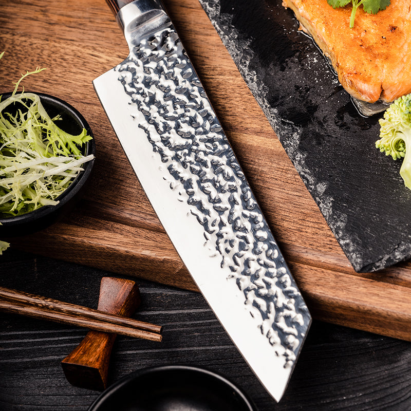 Hikari Knife Japanese chef's knife with a textured blade on a wooden cutting board with salmon and vegetables.