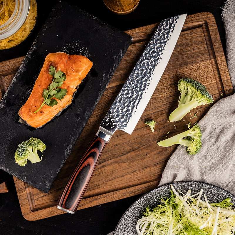 Salmon fillet with broccoli on a wooden cutting board with a professional japanese chef's knife.