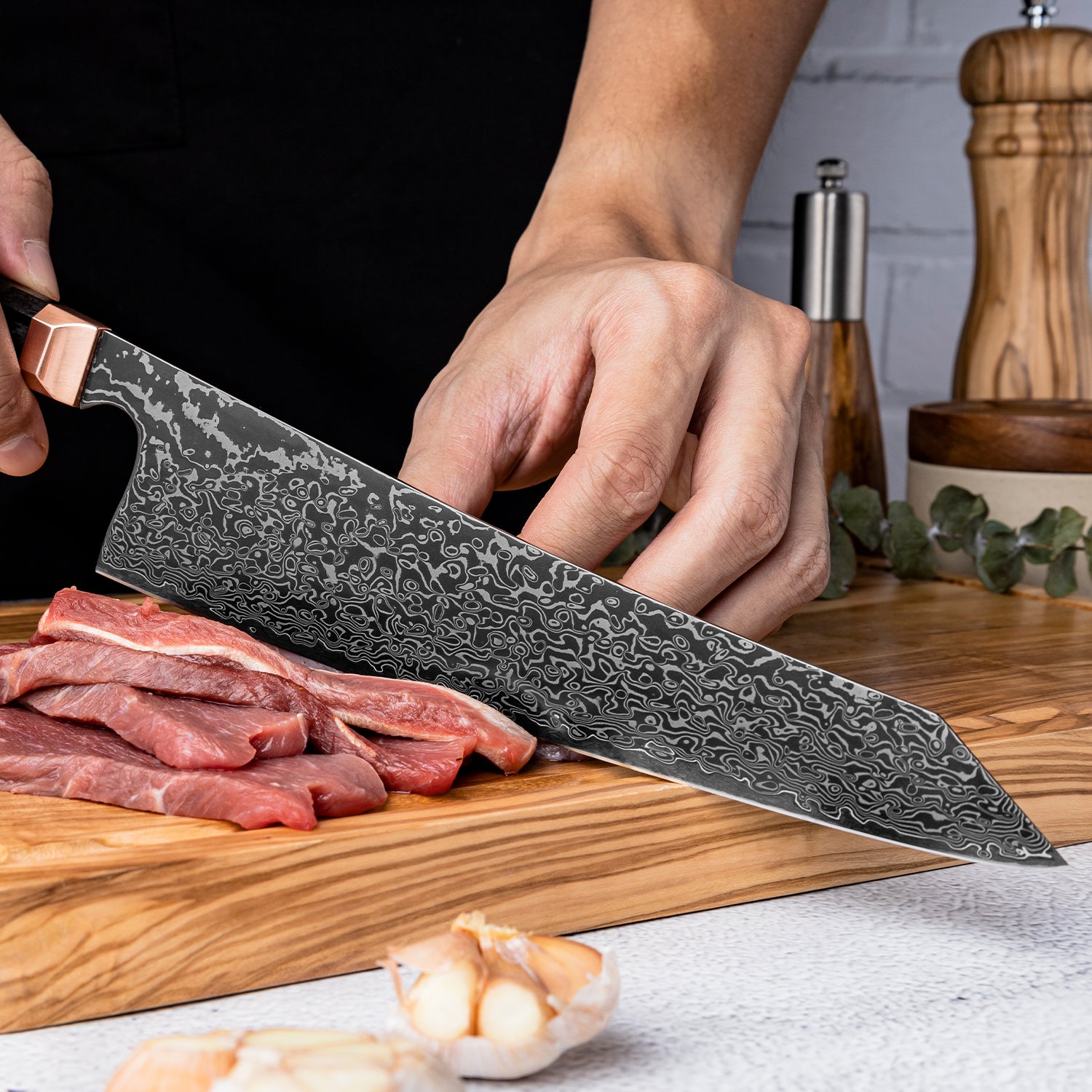 Person using a Damascus steel knife to cut meat on a wooden cutting board with a kitchen setting in the background.