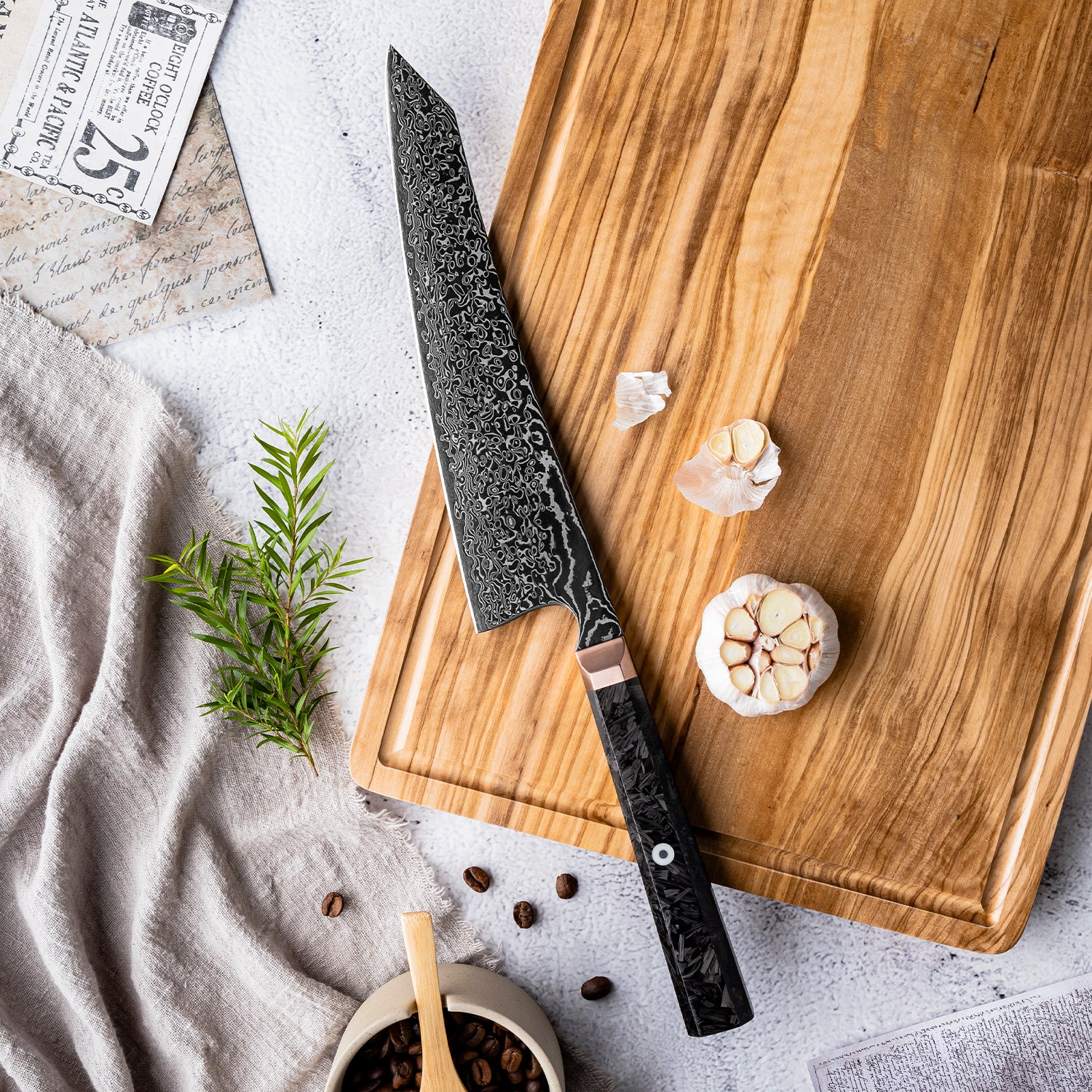 Decorative chef's knife on a wooden cutting board with garlic and herbs on a light gray surface.