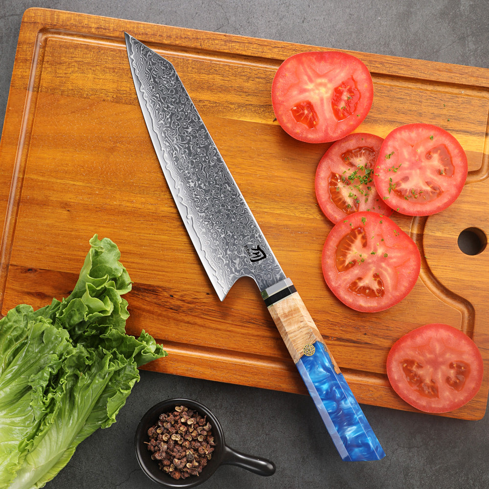 Chef's knife with a blue handle on a wooden cutting board with sliced tomatoes and lettuce.