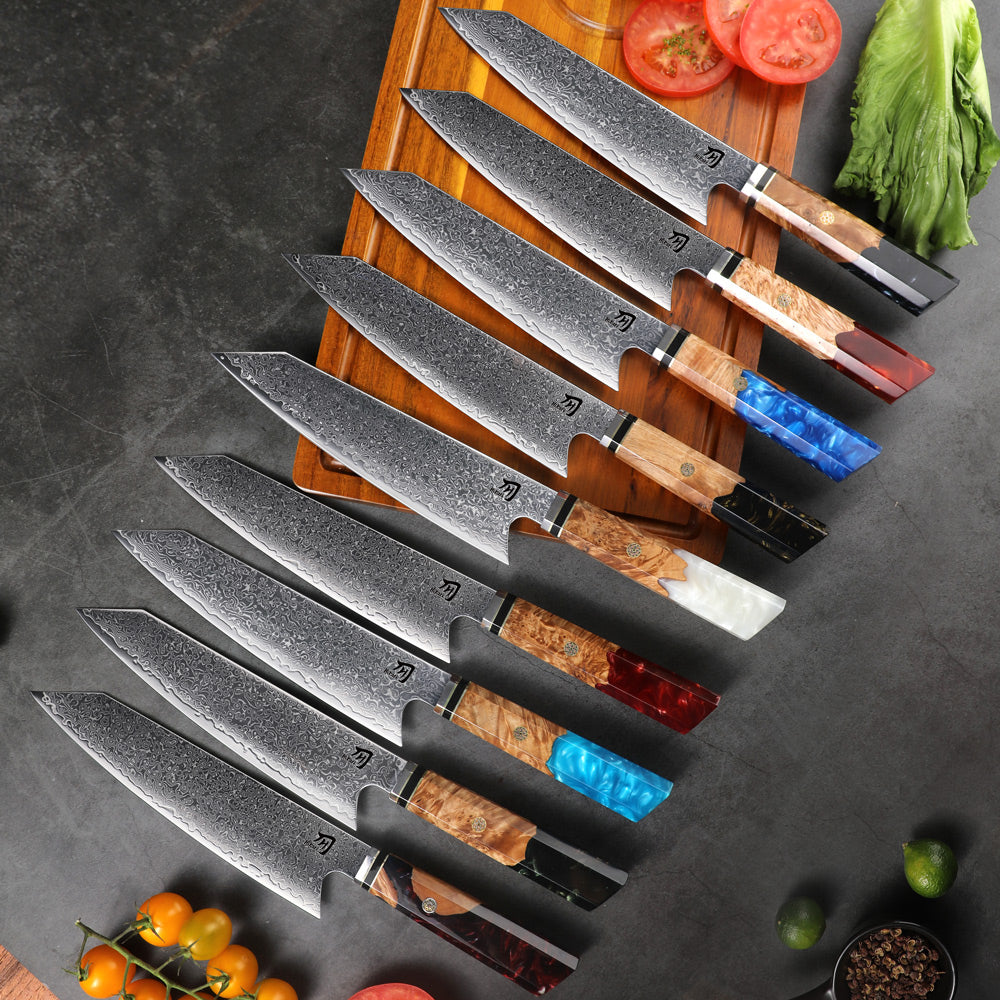 Set of chef knives with colored handles on a wooden cutting board with vegetables.
