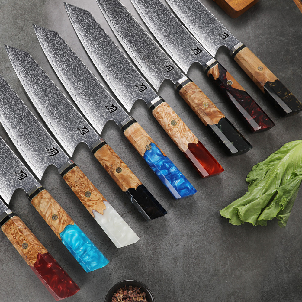 Set of chef knives with colored handles on a gray surface with vegetables.