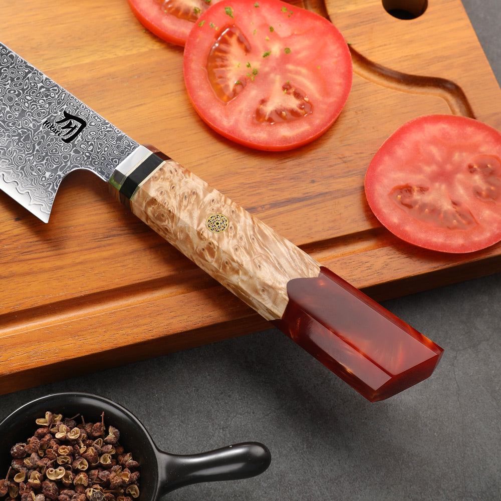 Chef's knife with a wooden handle and red blade on a cutting board with sliced tomatoes.