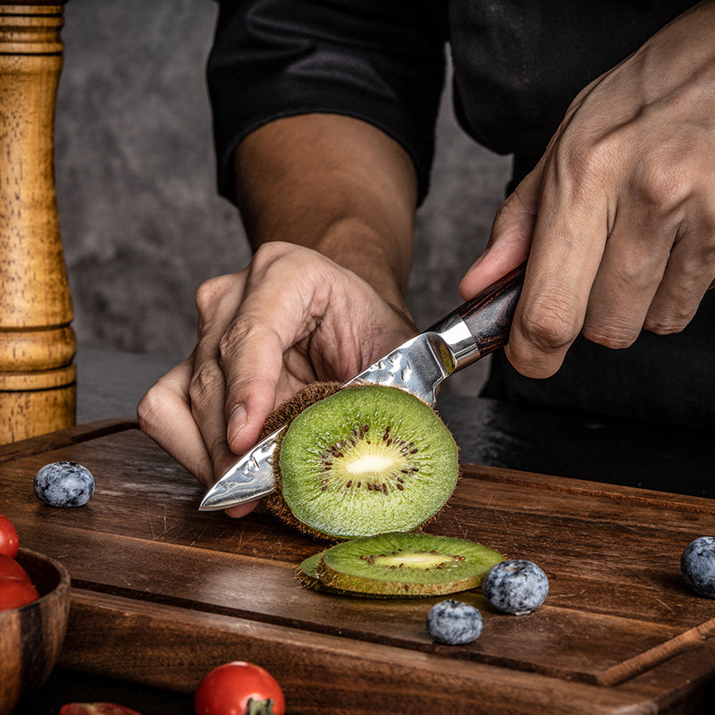 Person slicing a kiwi on a wooden cutting board with a Hikari Stainless Steel knife.