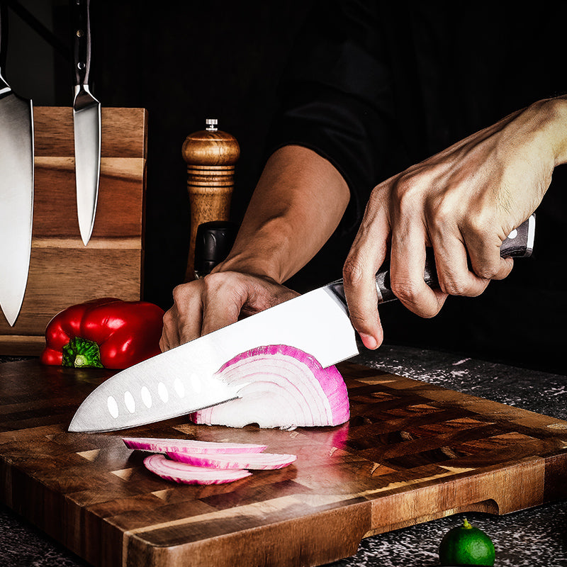Hikari knife santoku premium japanese chef slicing an onion on a wooden cutting board with kitchen utensils in the background.