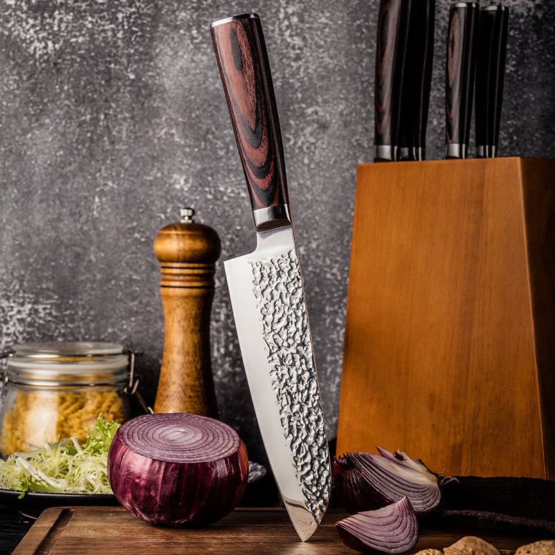 Japanese Professional Santoku knife with a wooden handle on a kitchen counter with onions and a pepper grinder.