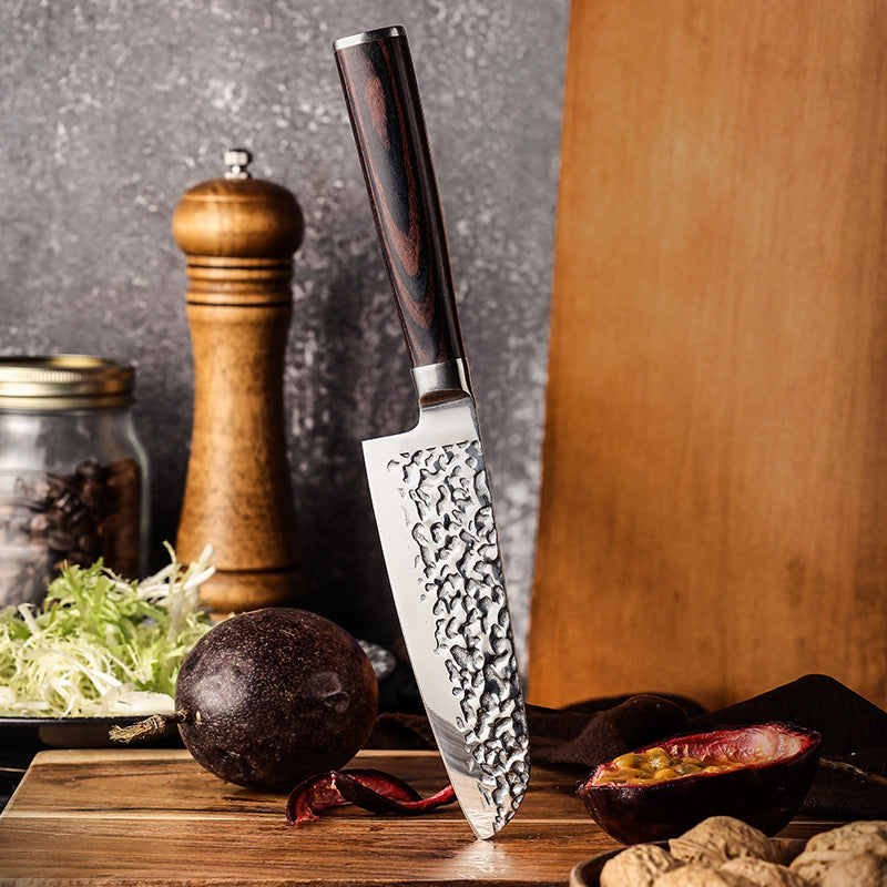 Hikari Santoku knife with a decorative blade on a wooden cutting board with vegetables.