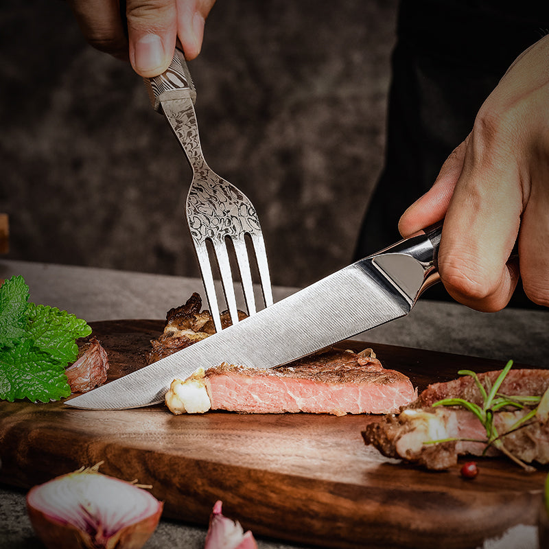 Person cutting a piece of meat with a premium german steel Hikari steak knife and fork on a wooden cutting board.